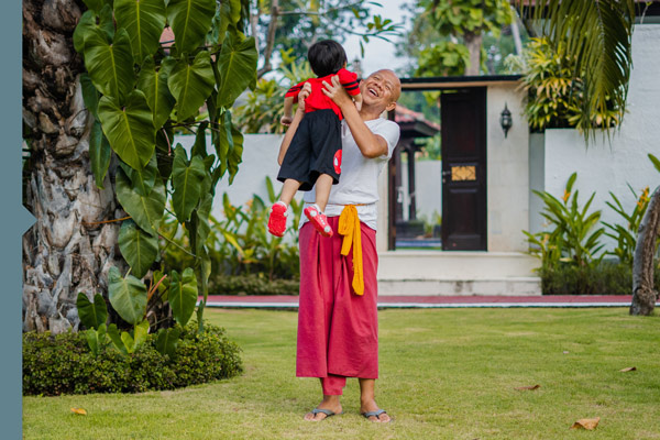 Social, laughing man with child in front of house, tropical plants, Indonesia, Bali